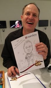 Cartoonist Stephen Doric holding a very flattering caricature of Eric Kontos.