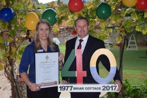 MP Greg Warren presents Briar Cottage director Jenelle Williams with a certificate to mark 40 years