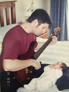 Mr Warren playing his guitar to son Bailey and a flyer from a gig Mr Warren played in 2001, below.